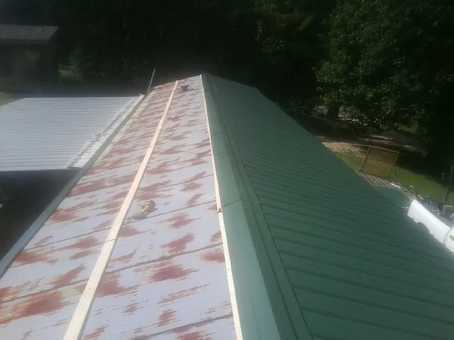 Old rusted panels beside newly installed green metal roofing — Wind Damage Roof Repair by Roofing Brothers in Fairplay