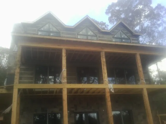Dormers and porch framing on a large log home under construction — Roof Coating work by our crew in Fairplay