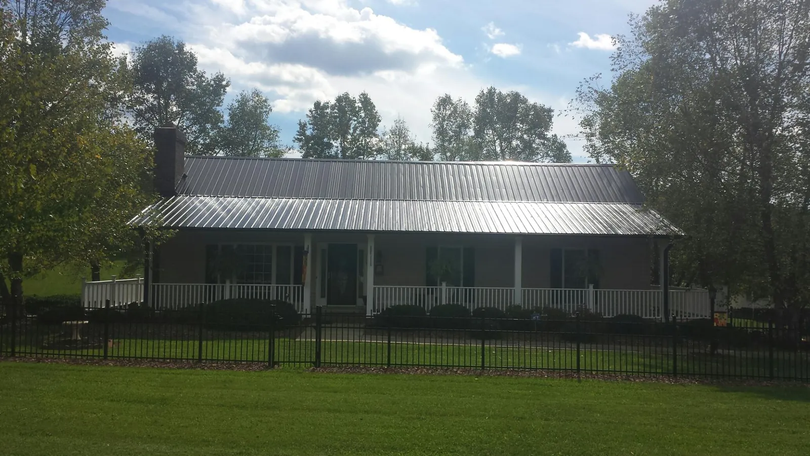 Gray metal roof on a brick ranch with a full width front porch — Gutter Guard Installation work by our crew in Fairplay