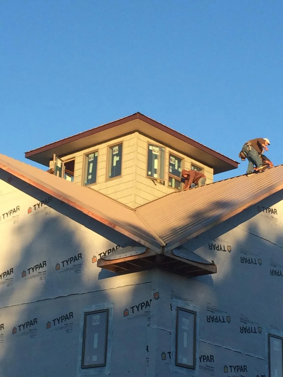 Roofers working around a rooftop cupola on a new metal roof at sunset — Roof Waterproofing in Fairplay by Roofing Brothers